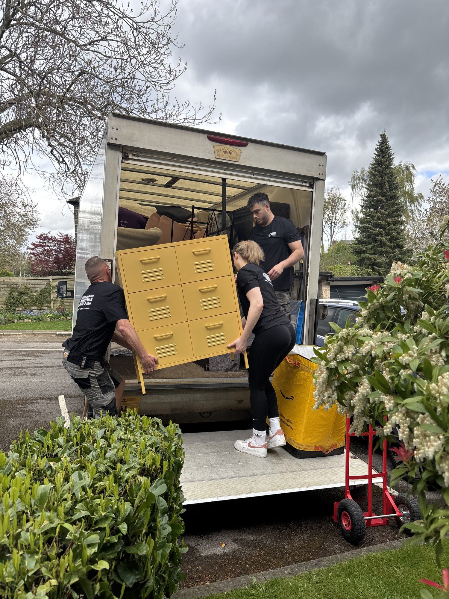 The crew loading a yellow chest of drawers into the Luton van